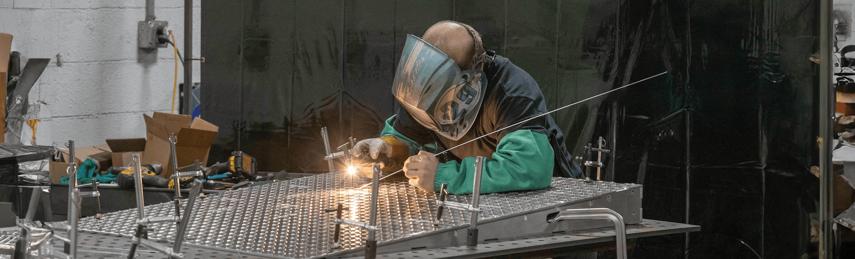 man in welding mask welding materials as part of metal fabrication